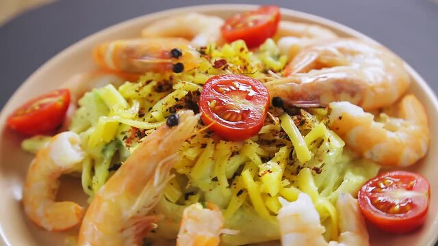 Pasta in a creamy sauce with shrimps in a plate rotates in a circle