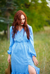 portrait of a beautiful red-haired young woman in a blue dress outdoors