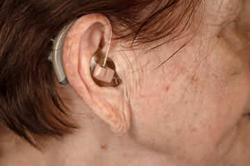 Hearing aid device in senior woman ear - closeup photo