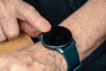 Smart watch (black screen - add your graphics) on elderly senior hand, closeup detail