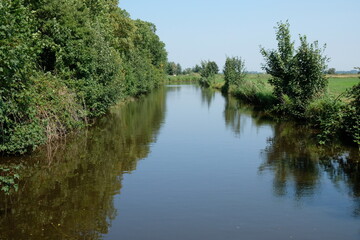 Fototapeta na wymiar FU 2020-08-11 Fries T2 536 Wasser in einem Kanal und darin spiegelt sich die Landschaft