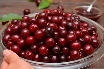 plate with ripe cherries in hand close-up