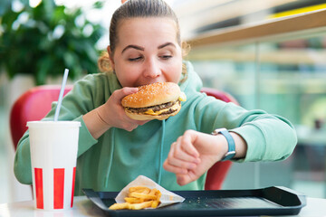Nervous stressed hungry girl, woman in hurry, rush biting, eating big burger, fries and soda...