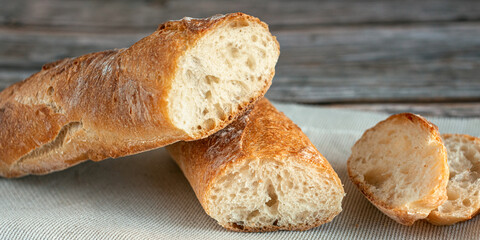 Sliced in half baguette. Beautiful bread close-up. Fresh baked bread loaf on wooden background. Tasty French bread.