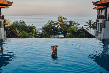 Woman on trip in bali enjoying swimming pool