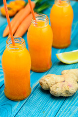 Glass of apricot and carrot juice on colourful turquoise blue painted wooden boards