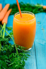 Glass of apricot and carrot juice on colourful turquoise blue painted wooden boards