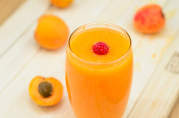 Glass of apricot and carrot juice on colourful turquoise blue painted wooden Glass of apricot and carrot juice on colourful turquoise blue painted wooden boards boards