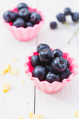 Chokeberry fruit in pink cup cake on a light wooden boards. Top View