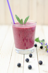 Cranberry and black currant smoothie in glass with cookies and mint on a white wooden background