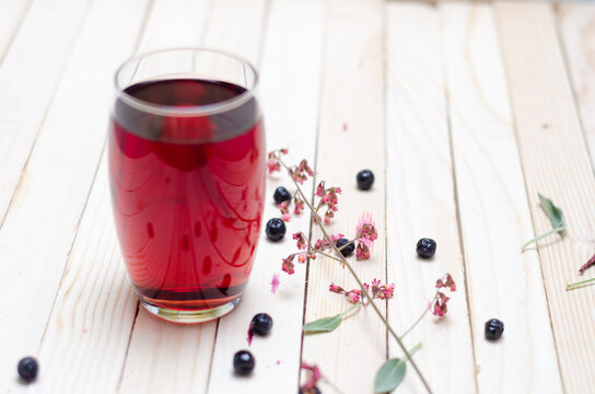 Cranberry and black currant juice in glass on a white wooden background