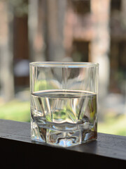 Glass shot with a transparent, colorless drink on a beautiful  wooden tabletop on a blurry, unfocused background