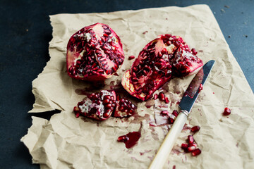 Pomegranates sitting on a wooden farm table with moody, dramatic light shining in from the right....