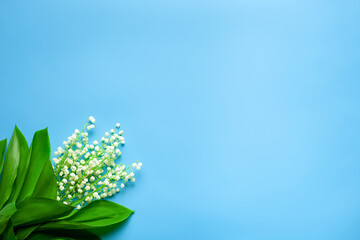 Bouquet of lilly of the valley in the corner with empty space. Flat lay with blue background. 