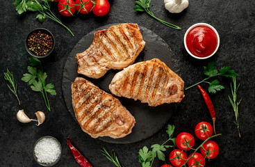 grilled pork steaks with spices on a stone background