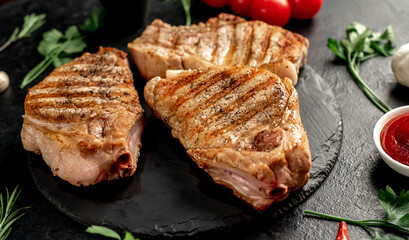 grilled pork steaks with spices on a stone background