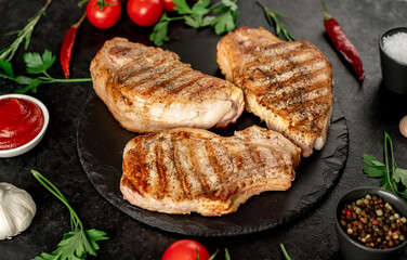 grilled pork steaks with spices on a stone background