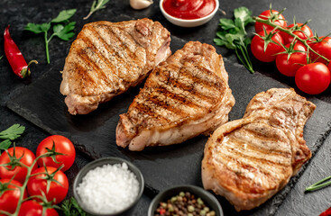 grilled pork steaks with spices on a stone background