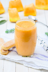 Glass of fresh cantaloupe smoothie with cookies  on white wooden boards.