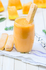Naklejka na ściany i meble Glass of fresh cantaloupe smoothie with cookies on white wooden boards.