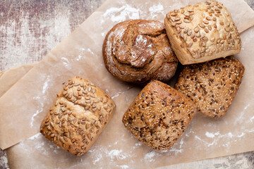 Gold rustic crusty loaves of bread and buns on wooden background. Still life captured from above top view, flat lay.