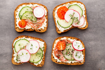 Sandwich with cereals bread and salami on dark marble background.