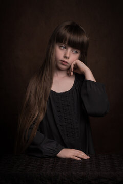 Classic portrait of young girl sitting and thinking in studio