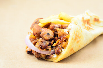 Traditiona Greek pita gyros with meat, fried potatoes.  Placed on brown paper