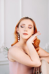 portrait of a freckled woman with closed eyes with mother-of-pearl pearls on her face and hand on a...