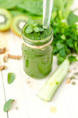 Healthy green smoothie with spinach, kiwi and orange in a retro jar on light wooden table. Top View