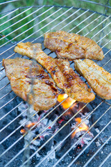 Chuck steaks being barbequed outdoors
