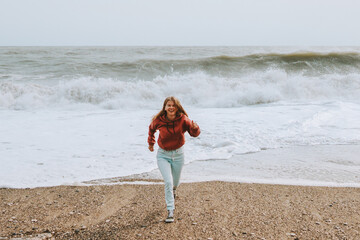 Happy woman running at stormy sea  beach positive emotions healthy lifestyle happiness and freedom...