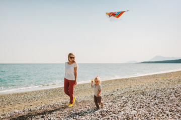 Mother and child walking on beach family travel vacations kite flying healthy lifestyle outdoor mom...