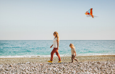 Family vacation mother and daughter walking on beach with kite flying travel healthy lifestyle mom...
