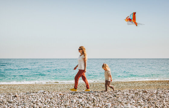 Family vacation mother and daughter walking on beach with kite flying travel healthy lifestyle mom and child outdoor enjoying sea view