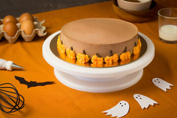Making Chocolate halloween cake, handmade Pumpkin Pie with Ingrediends on the Kitchen Table.