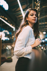 Half length portrait of young Caucaisan woman dressed in smart casual white shirt looking at camera during leisure pastime in shopping center, attractive female with natural beauty posing indoors