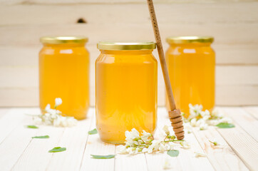 Three Locust Honey Jars with locust blossoms and flowers on retro wooden table. Close-up