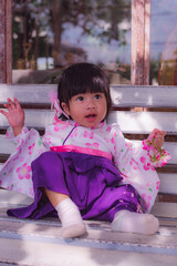 Adorable little girl wearing Japanese kimono in the park with soft focus.