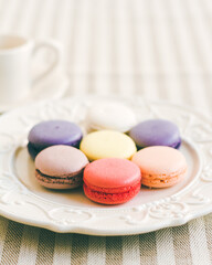 Different coloured macarons on white retro plate. Selective Focus