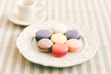 Different coloured macarons on white retro plate. Selective Focus