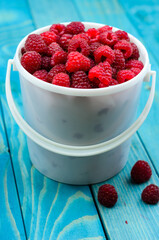 Raspberry bucket on colourful turquoise blue painted wooden boards