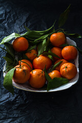 Tangerines in bowl on the black paper