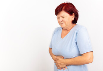 Mature woman experiencing stomach pain and cramps against a white background