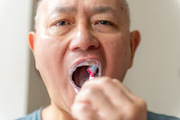 Close up of a man brushing his teeth with a tooth brush.