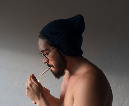 chico blanco con gorro encendiendo un cigarrillo