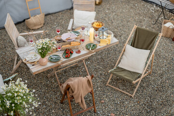 Beautifully served wooden table in natural boho style outdoors. Dining table decorated with field...