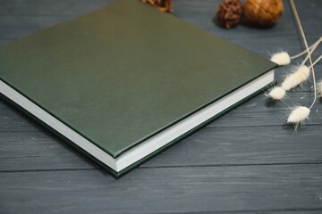 Fototapeta premium Green wedding or family photo book with leather cover. stylish wedding photo album close up. family photoalbum on wooden background.