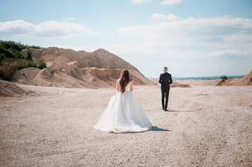 Fototapeta na wymiar Newlyweds walk and hug in a sandy quarry