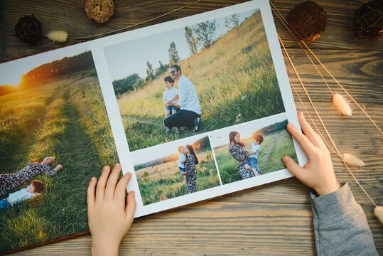 the Hand child holding a family photo album against the background of the a wooden table